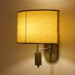 Soft yellow wall lamp with a textured shade casts a warm glow indoors.