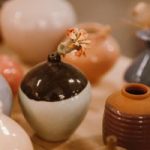 A collection of artistic ceramic vases displayed with a floral touch, showcasing glazed finishes and various colors.